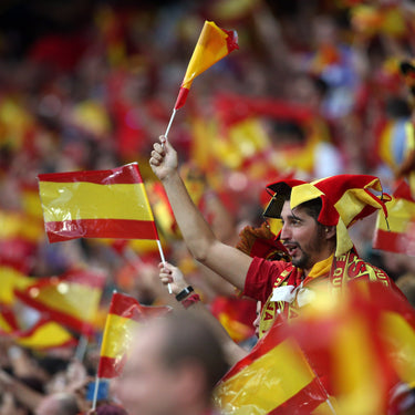 Fan waving a Spanish flag in a crowd of people with Spanish flags